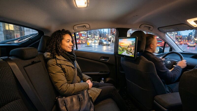 A passenger in a Harlow taxi with a Space4Promotion screen on the headrest in front of her